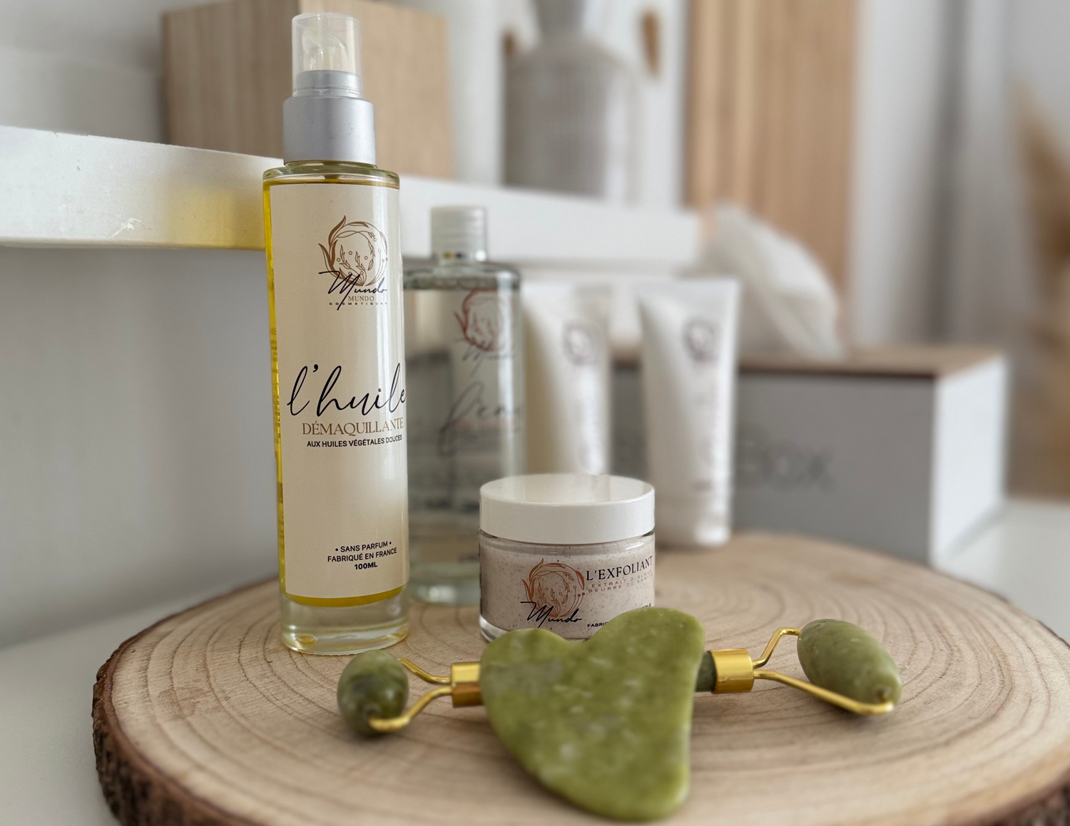 Image de la gamme de produit Mundo sur un rodin de bois avec une huile, des crèmes, un gua sha