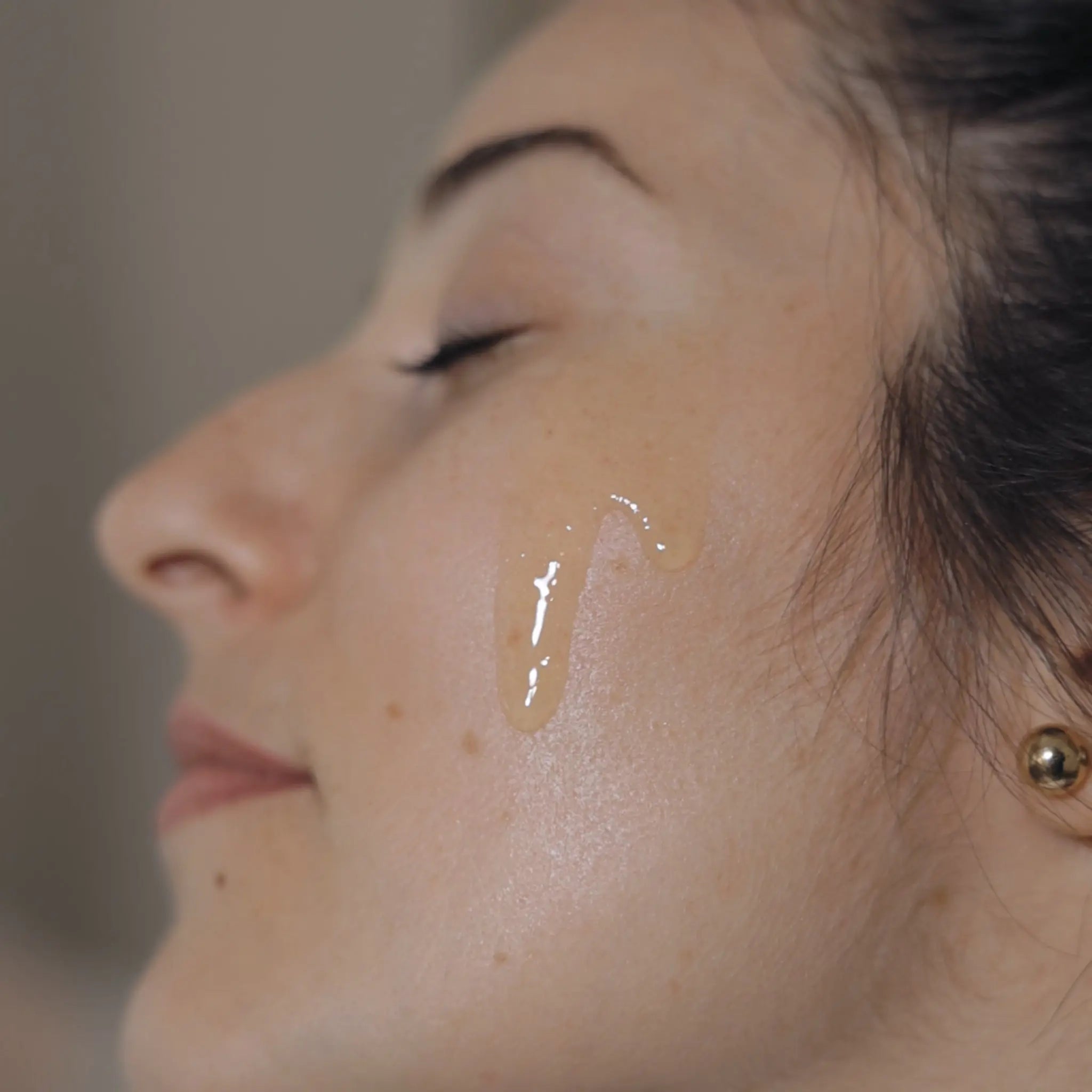 Image de l'huile démaquillante coulant sur la peau d'une cliente